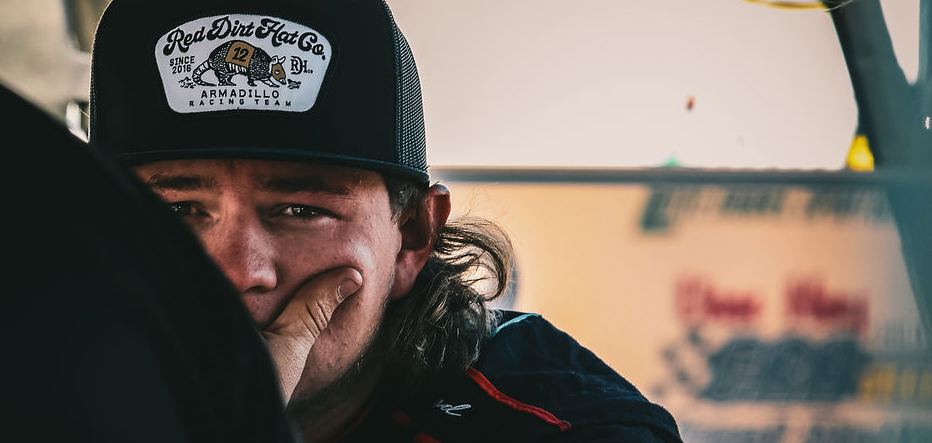 Close-up of Jett Noland wearing a Red Dirt Hat Co. cap, focused and contemplative before a race event