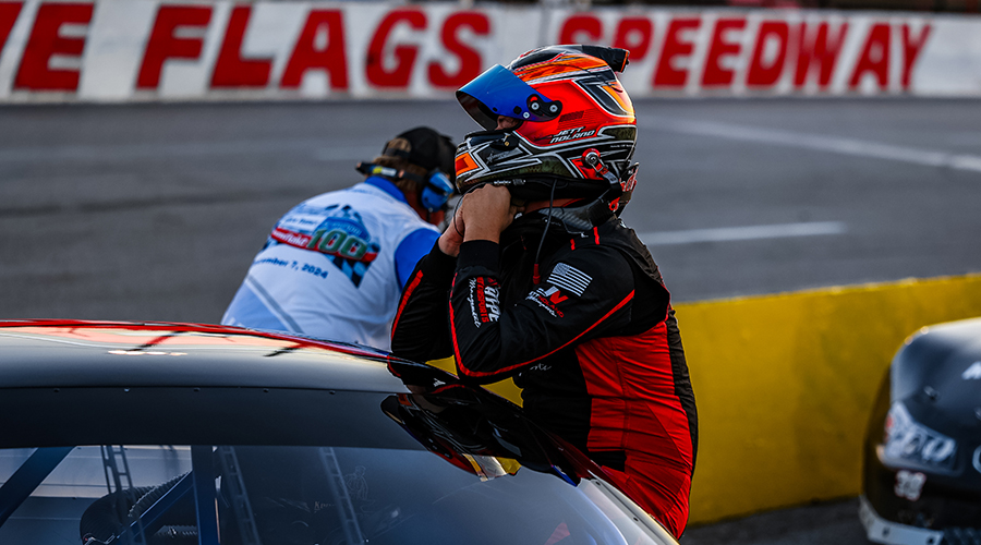 Jett Noland, driver of the #50 car, prepares for the race at Five Flags Speedway on September 7, 2024, showcasing his racing gear and helmet beside his car on the track.