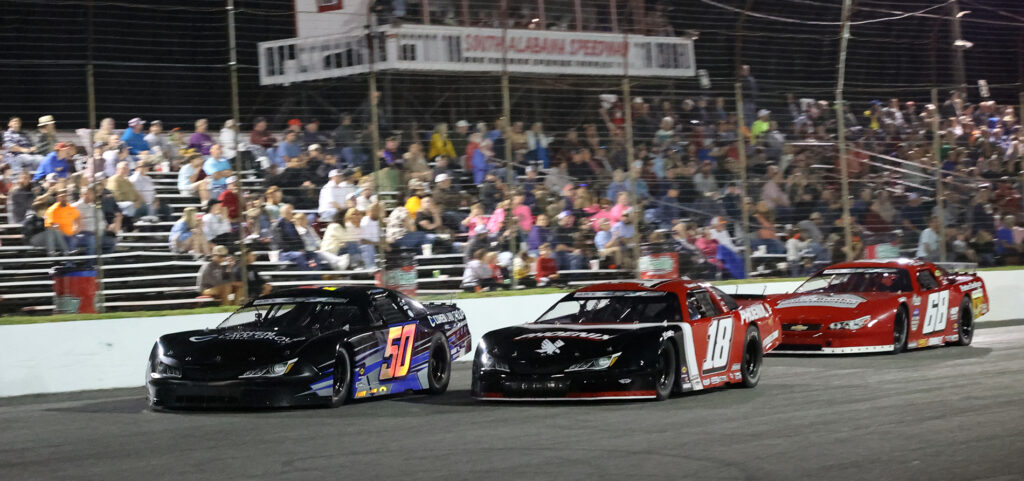 Jett Noland #50 racing side-by-side at South Alabama Speedway in front of a packed grandstand during a high-intensity racing event